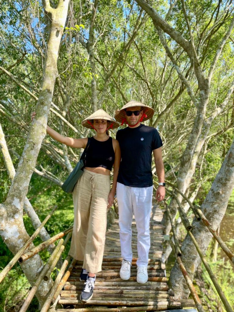 A couple standing under tall bamboo trees, enjoying the peaceful nature at Lung Ngoc Hoang Nature Reserve.