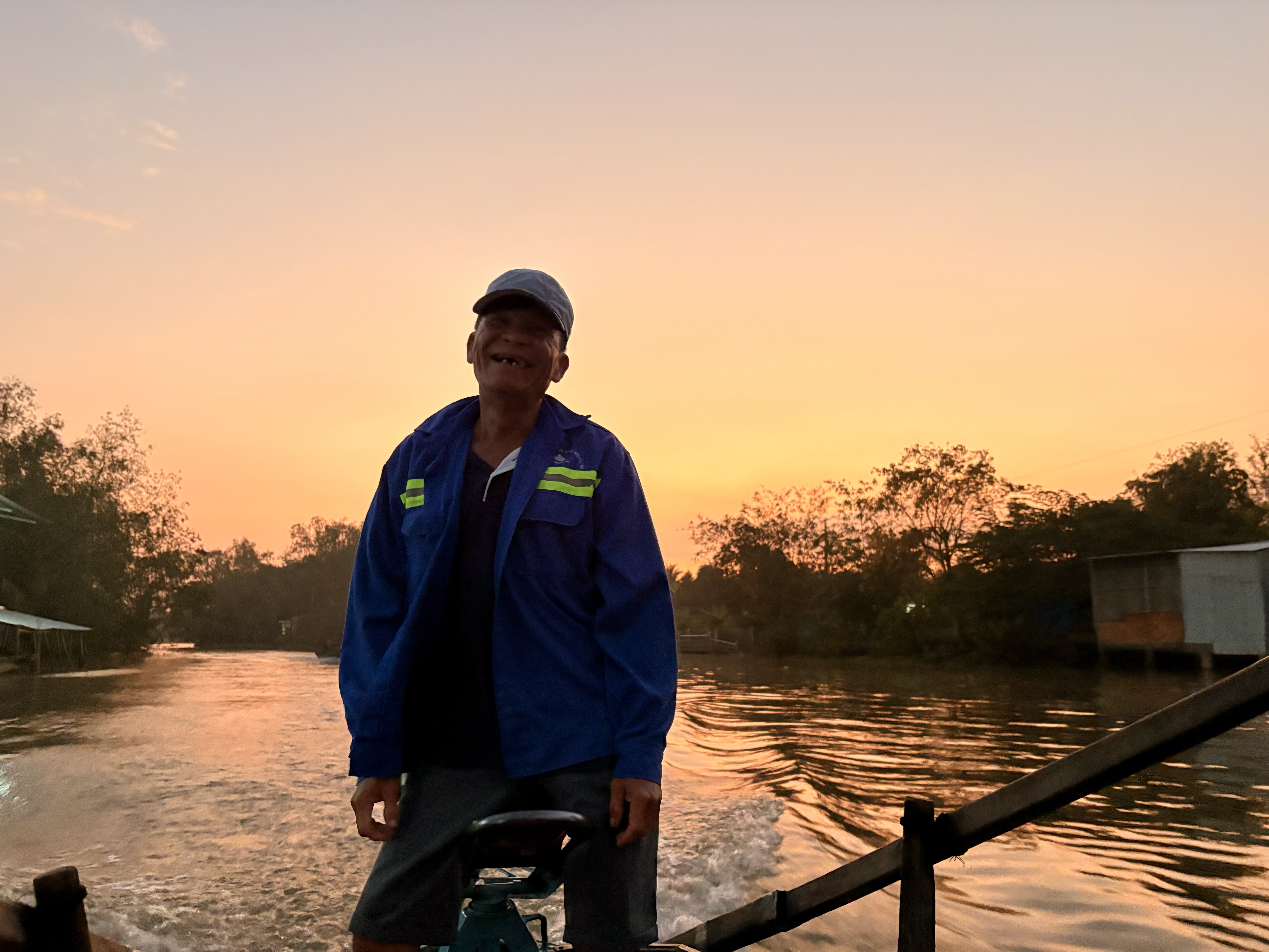 Local boat driver navigating the Mekong Delta at sunrise during a Can Tho floating market tour.