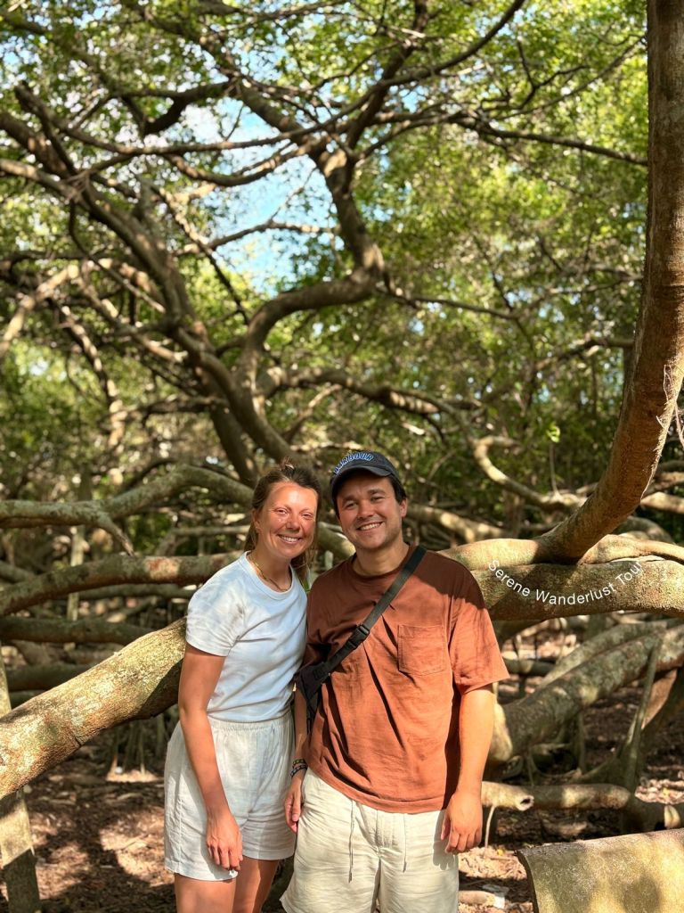 Bike tour couple posing beneath ancient tree branches in Can Tho.